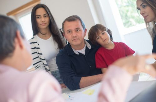 A family of four seeks advice from a professional during an indoor consultation in a bright room.